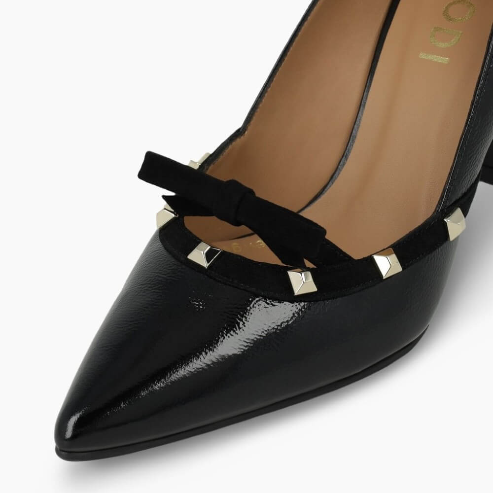 Black high-heeled shoe with decorative bow and studs on a white background Lodi RERIS pumps in black patent leather