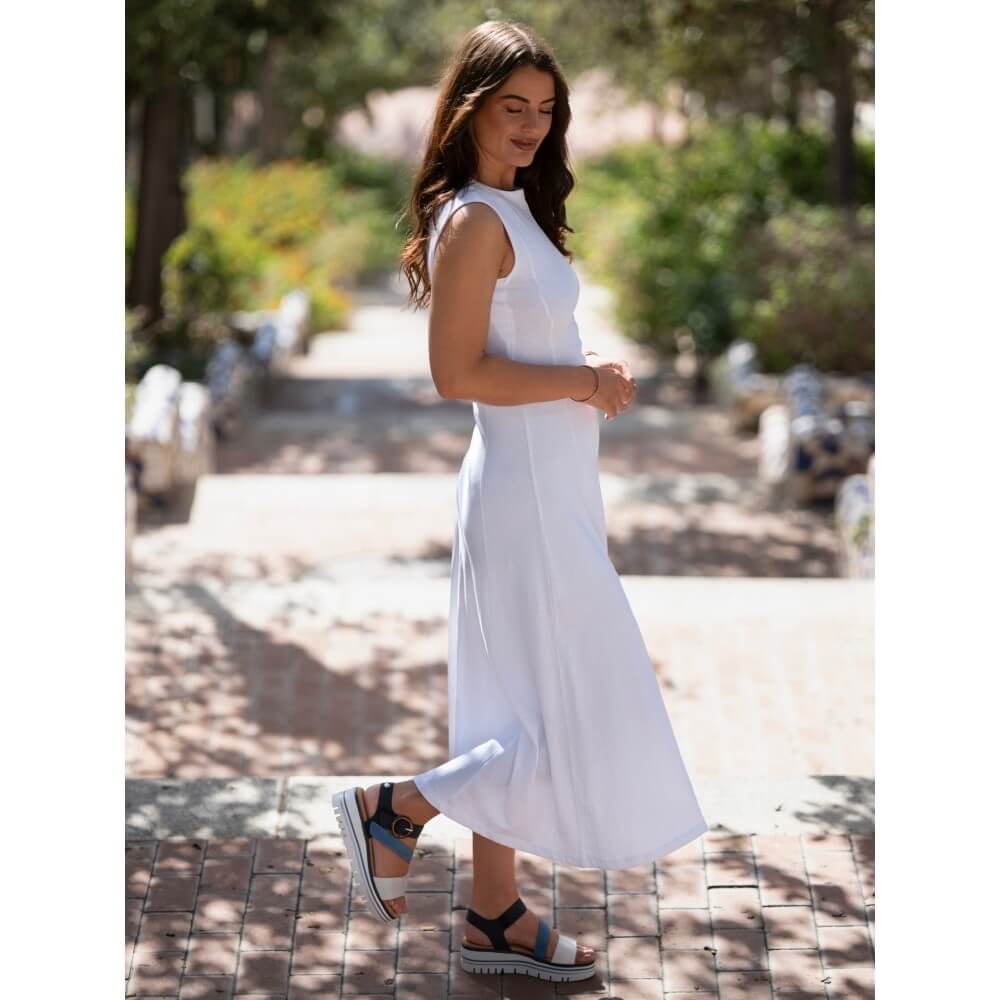 Woman in a white dress and lunar blue sandals walking outdoors on a sunny day