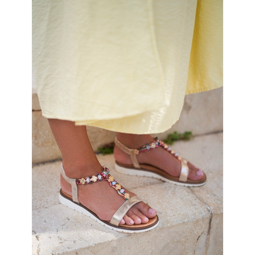 Lunar Beaded sandals worn with a yellow skirt on a stone surface